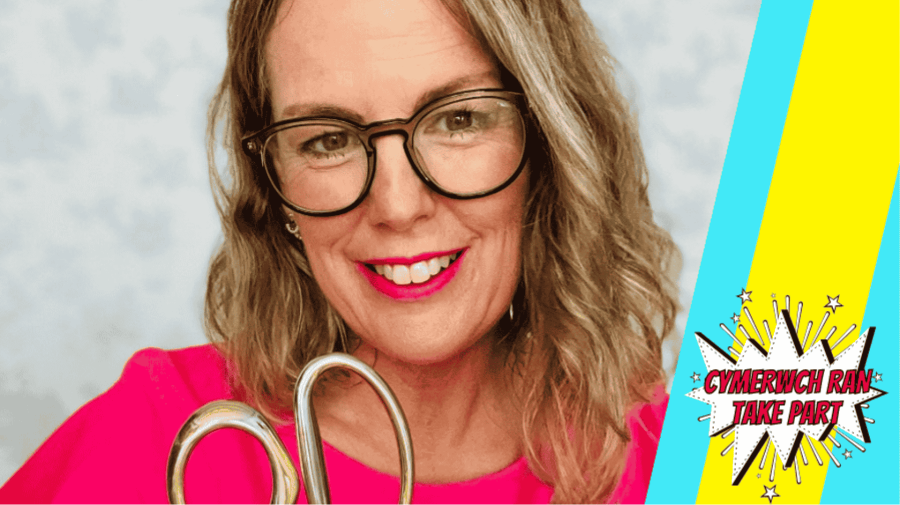 a white woman with big framed glasses holding a giant pair of gold scissors 