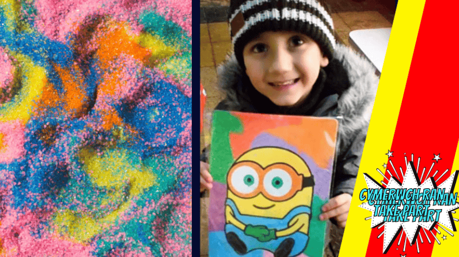 multi coloured sand in pink blue and green, with a photo of a small child in a brown and white bobble hat holding a picture of a Minion made from coloured sand 