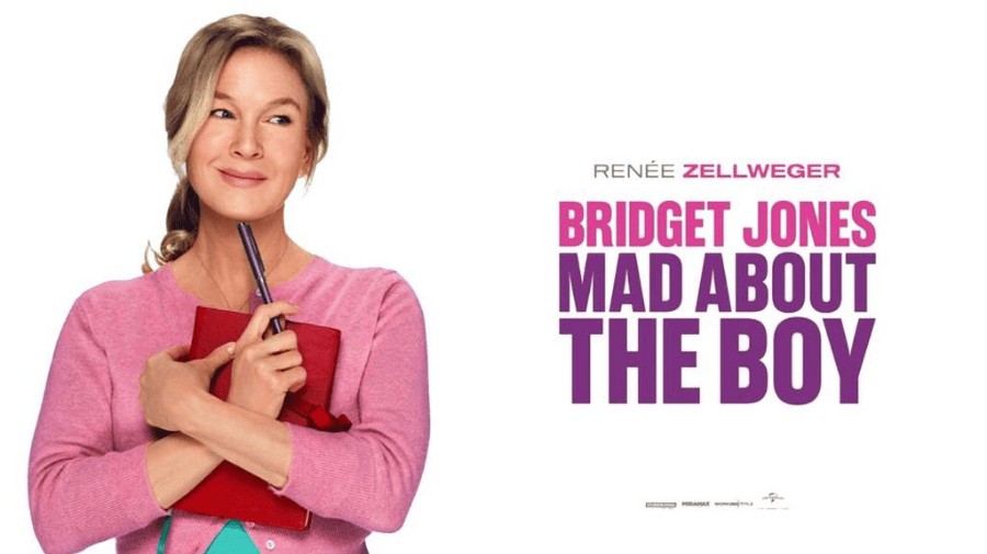 renee zellweger as bridget jones - a white woman with long blonde hair tied back, in a pink cardigan, clutches a red book to her chest and smiles 