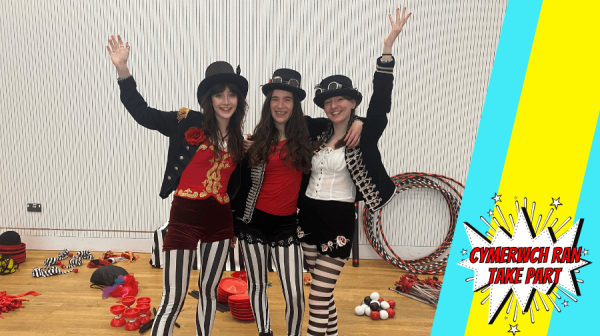 three young women in circus clothes wave at the camera