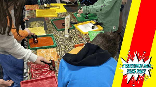 a group of people crowded around a table making colourful art patterns 