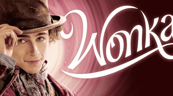 Timothy Chalamet as Wonka. In a brown jacket and he's tipping a brown top hat. The word Wonka in gold filigree lettering to the right of him 