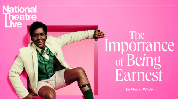 a pink background and white lettering National Theatre Live The Importance of Being Earnest. A young black man wears a light yellow jacket, green shiny waistocoat and shorts. he has one knee higher than the other and is holding onto a wooden bannister with his left hand 